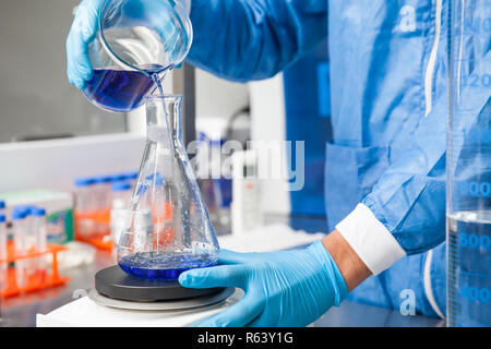 Junge männliche Wissenschaftler arbeiten mit einem Rührwerk im Labor in Blau gekleidet Stockfoto