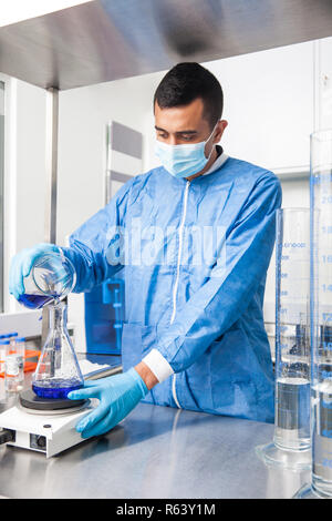 Junge männliche Wissenschaftler arbeiten mit einem Rührwerk im Labor in Blau gekleidet Stockfoto