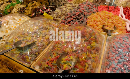 Große Stapel von eine Auswahl an Süßigkeiten und Gummies auf großen Tabletts im Süßwarenladen. Stockfoto