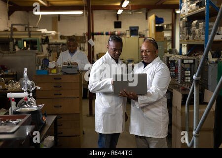 Männliche Arbeitnehmer diskutieren über einen Laptop in Glashütte Stockfoto