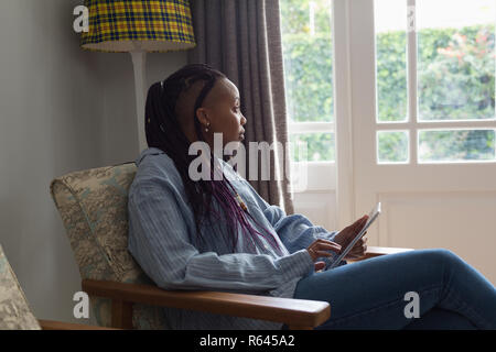 Nachdenkliche Frau mit digitalen Tablet in einem liviing Zimmer Stockfoto