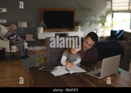 Vater, der seine Tochter zu helfen, die in den Studien im Wohnzimmer Stockfoto