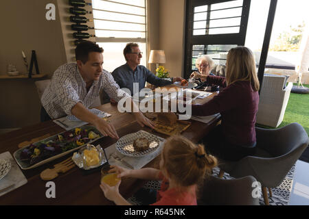 Familie in Essen am Esstisch im Wohnzimmer. Stockfoto