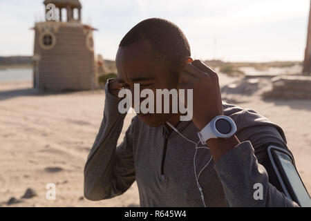 Männliche Athleten mit Kopfhörer in der Nähe von Strand Stockfoto