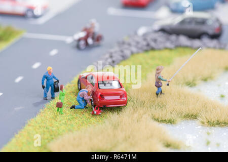 Miniatur Mechaniker Austausch einer defekten Reifen weg von der Fahrbahn Stockfoto