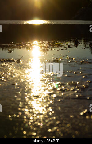 Neu auferstandenen Sun befindet sich auf einem teilweise zugefrorenen See spiegelt, Erstellen einer Linie der unterschiedlichen Sonneneinstrahlung. Die Sonne selbst ist nicht sichtbar. Stockfoto