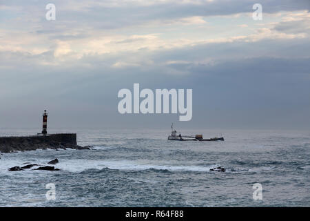 Moody seascape sehen Schiff, Bagger, Verlassen der Flussmündung nach baggerarbeiten am Ende des Tages. Im Norden von Portugal. Stockfoto