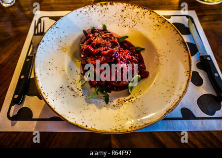 Süße rote Pflaumen mit gegrilltem Steak und grüne Blätter auf einer Platte Stockfoto