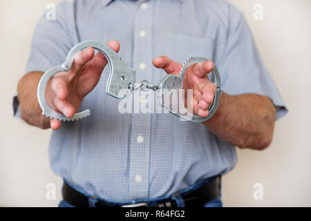 Der Mann hält die Handschellen in seiner ausgestreckten Hand. Close Up. Stockfoto