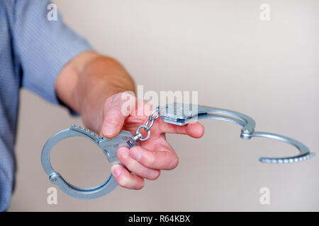 Ein Mann hält offen Handschellen in seiner ausgestreckten Hand. Close Up. Stockfoto