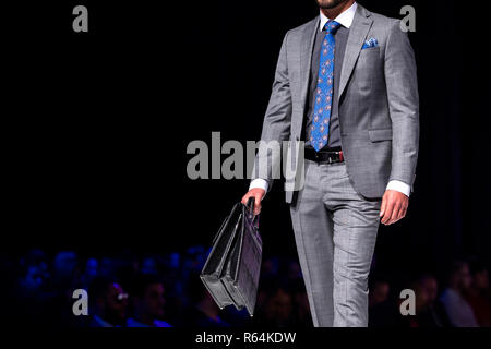 Männliches Modell geht der Start- und Landebahn in Silber Anzug während einer Modenschau. Fashion Catwalk Ereignis zeigt neue Sammlung von Kleidung. Single Modell isoliert auf einem Stockfoto