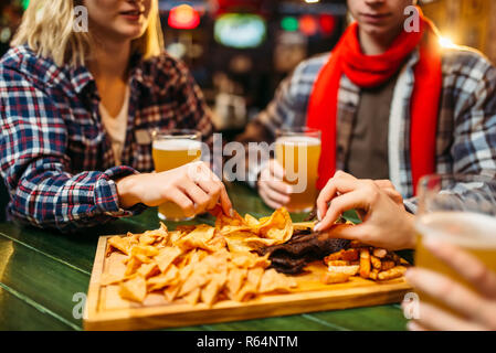 Fußball-Fans trinkt Bier und isst Chips am Tisch in der Sports Bar. Sieg feiern, die TV-Ausstrahlung, junge Freunde Freizeiten im Pub Stockfoto