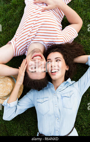 Bild von der Oberseite des liebenden Menschen Mann und Frau 20 s Neben gegenüber Köpfe liegen auf grünen Gras im Park Stockfoto