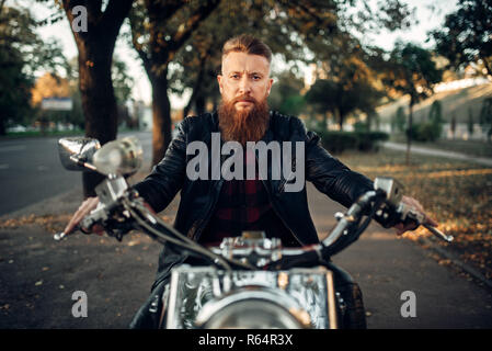 Bärtige Motorradfahrer in Leder Jacke sitzen auf klassischen Chopper, Vorderansicht. Vintage bike, Reiter auf Motorrad Stockfoto