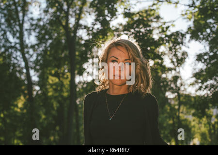 Porträt einer blonden Frau zu Fuß in einem Park auf einem warmen sonnigen Tag Stockfoto