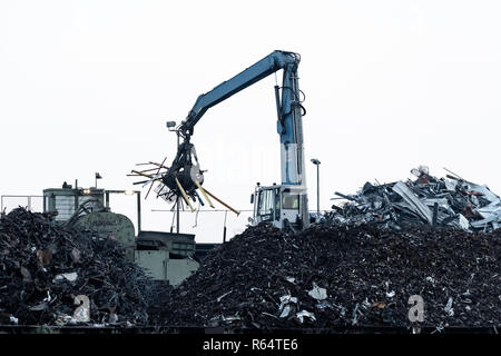 Ein Kran mit Greifer in Aktion auf Recyclinghof. Stockfoto