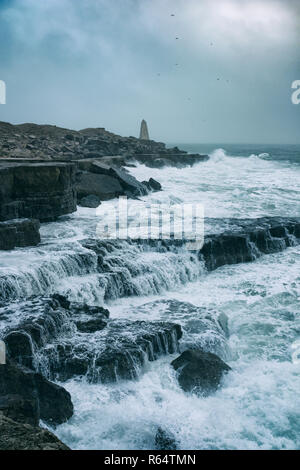 Trinity House Obelisk und stürmischer See an der Portland Bill, Dorset, England. Stockfoto