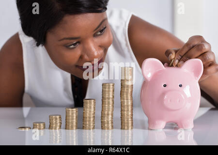 Die menschliche Hand Münze in Sparschwein Stockfoto