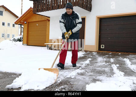 Ein Mann schaufeln Schnee vor den Garagen Stockfoto