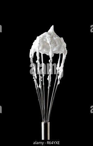 Ein metall Schneebesen mit Eischnee, durch einen schwarzen Hintergrund mit Kopie Raum dargestellt. Zutat für Dessert Stockfoto