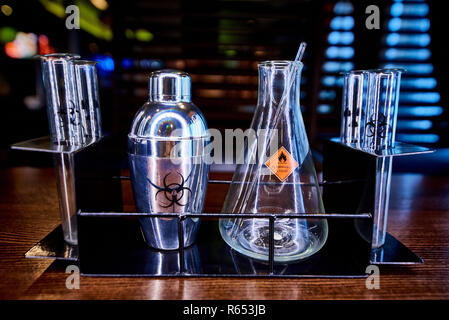 Shaker, Kolben und Reagenzgläser mit dem Symbol der biologische Gefahr, brennbare Flüssigkeiten und Strahlung auf ein Metall Rack. Stockfoto