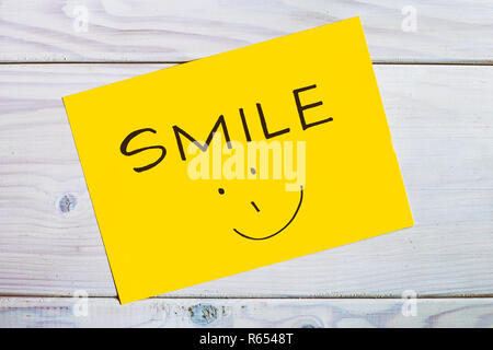 Wort Lächeln und Smiley auf hölzernen Tisch. Stockfoto