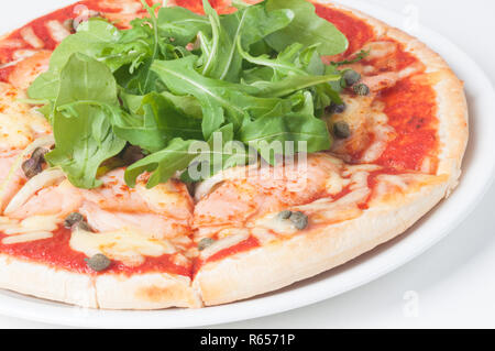 Lachs Pizza mit frischem Rucola Salat und Kapern Stockfoto