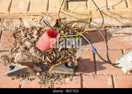 Lose Drähte Strom aus der Bürgersteig in einem öffentlichen Park. Stockfoto