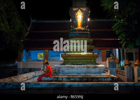 Junger Mönch mit einem Handy in Wat Sensoukaram Buddhismus Tempel in der Stadt Luang Prabang Laos Stockfoto