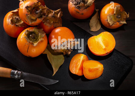 Persimone noch Leben in einer Low Key. Organische Kakifrucht im Herbst geerntet. Ansicht von oben. Diospyros kaki Stockfoto