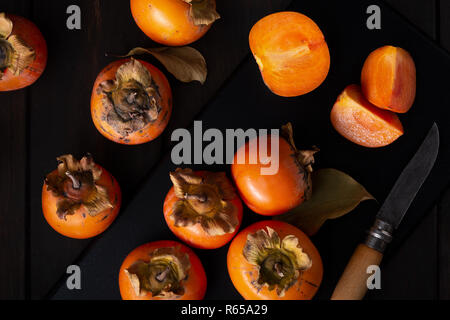 Persimone noch Leben in einer Low Key. Organische Kakifrucht im Herbst geerntet. Ansicht von oben. Diospyros kaki Stockfoto