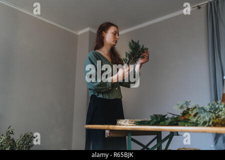 Foto der jungen kaukasischen Blumenhändler, die Schneiden ist eine Tanne Verzweigung vor ein Client in Ihrem eigenen Blumenladen Stockfoto