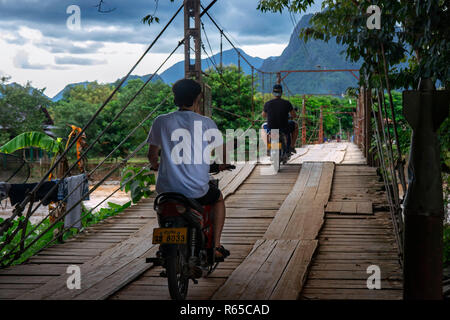 Motorrad Kreuzung hölzerne Brücke über den Fluss Nam Song in Vang Vieng, Laos Stockfoto