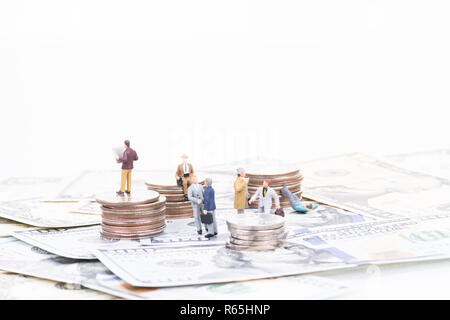 Miniatur Geschäftsleute auf Münzen und Banknoten Stockfoto