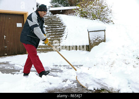 Ein Mann schaufeln Schnee vor den Garagen Stockfoto