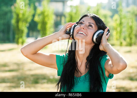 Frau mit Kopfhörer genießt Musik Outdoor. Stockfoto