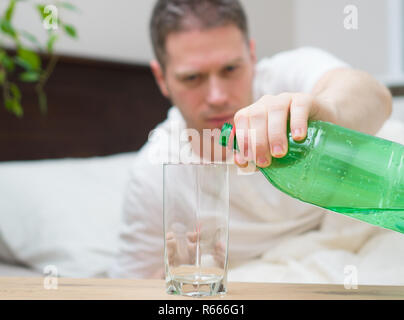 Mann trinken Wasser und Leiden von Kater. Stockfoto