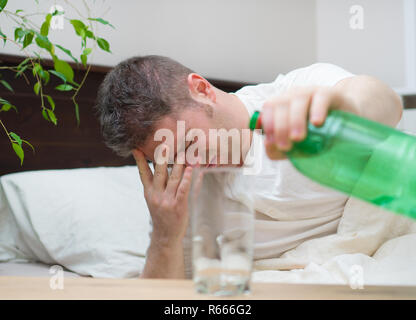 Mann trinken Wasser und Leiden von Kater. Stockfoto