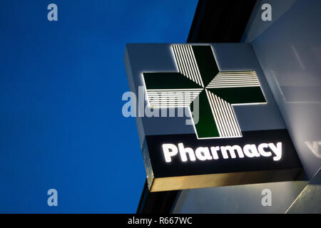 Nahaufnahme eines beleuchtete grüne Medizin Apotheke Kreuz bei Lloyds Chemiker unterzeichnen in der Dämmerung im Dinnington, Rotherham, Großbritannien Stockfoto