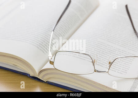 Close up Gläser und offenes Buch auf dem Schreibtisch Stockfoto