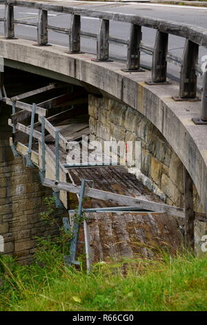 Noch nicht ganz herausgefunden, was mit den erhöhten Holzplanken unter der Autobahnbrücke in den Alpen gehen Stockfoto