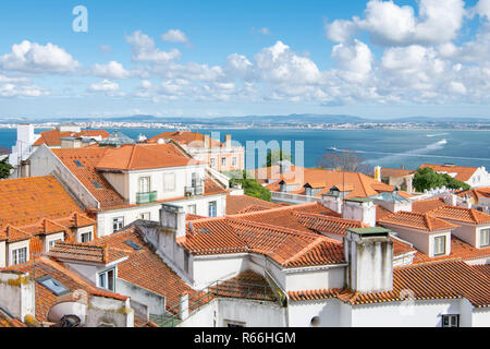 Blick über die roten Ziegeldächer der Alfama unter einem wunderschönen blauen Himmel mit weißen Wolken Puffy in Lissabon, Portugal Stockfoto