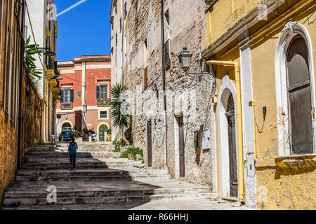 Eine junge Schülerin Spaziergänge in den Schatten einer Gasse Treppe im historischen Zentrum von Brindisi, Italien Stockfoto