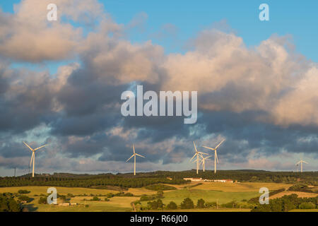 Landschaft von alten Bauernhöfen und Feldern mit modernen Windmühlen unter einem schönen Himmel kontrastiert mit geschwollenen Wolken bei Sonnenuntergang in der portugiesischen Region Alentejo Stockfoto