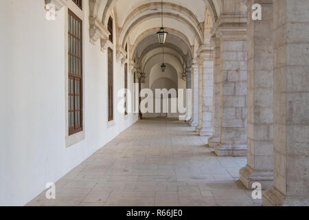 Langer Gang, der Perspektive unter Bögen mit Spalten auf einer Seite und eine weiße Wand auf der anderen Seite in Lissabon, Portugal Stockfoto