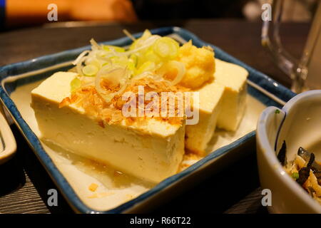 In der Nähe von kleinen Teller mit Tofu mit gehackten Zwiebeln und gebratenen Zwiebel Flocken Stockfoto