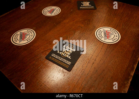 Beermat in einem kleinen Pub Förderung der lokalen Pub lesen "Lang lebe die Lokalen". Dargestellt in Chichester, West Sussex, UK. Stockfoto