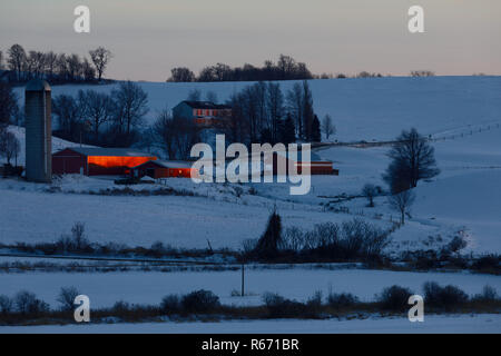 Spät sun off blinkt eine rote Scheune in schneebedeckten Feld, in Waterville, Oneida County, New York State, USA. Stockfoto