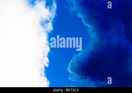 Kontrast zwischen weißen und dunklen blauen Wolken im blauen Himmel Stockfoto