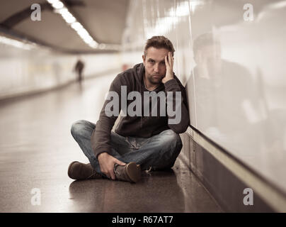 Traurige junge Mann weinen leiden Depression stress sitzen auf dem Boden Street U-Bahn Tunnel suchen verzweifelt lehnte sich an der Wand allein in der psychischen Störung Emo Stockfoto